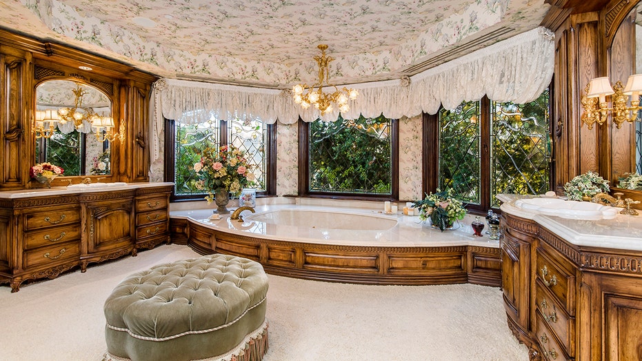 an expansive look at the bathroom with a green ottoman