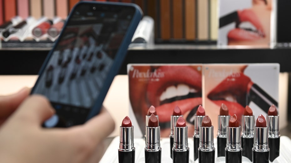 A person taking a photo of lipstick on display