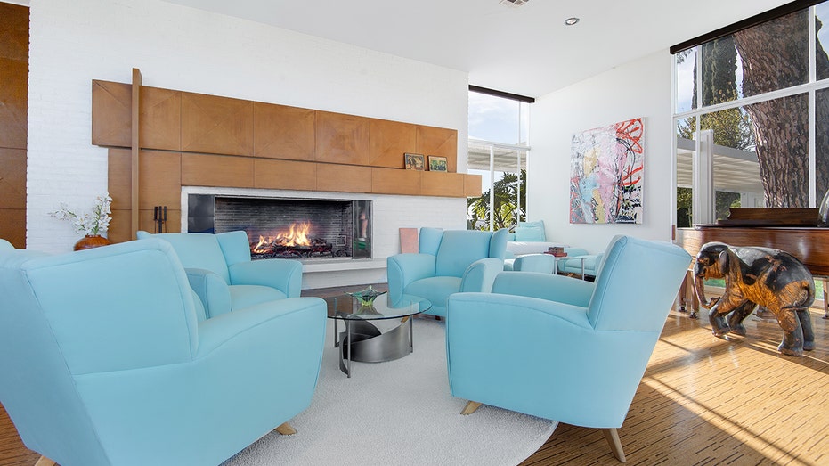 The entertainment room features a fireplace, piano and baby blue armchairs.