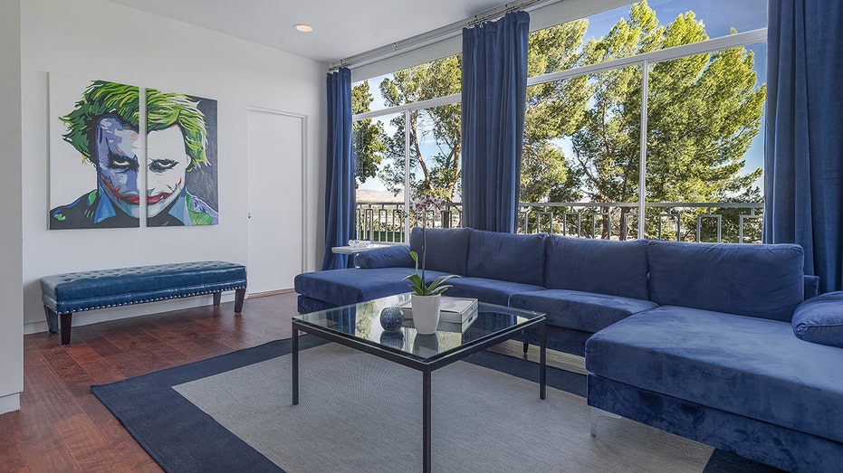 There is an additional sitting room which features blue furniture and a Joker painting.