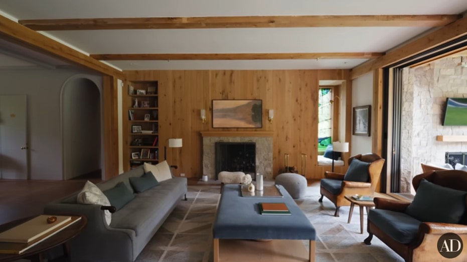 The living room also features wooden paneling, built-in bookshelves and a fireplace.