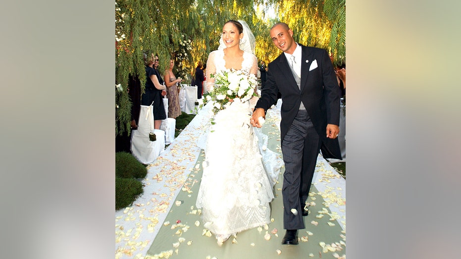 Jennifer Lopez beams in a white wedding dress walking down the aisle with husband Cris Judd