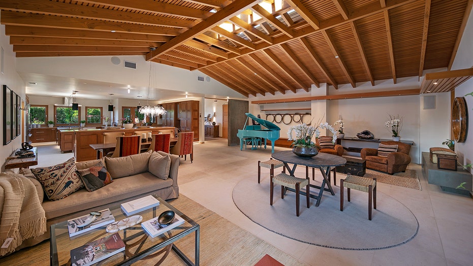 The great room features a blue grand piano, a fireplace and the dining room.