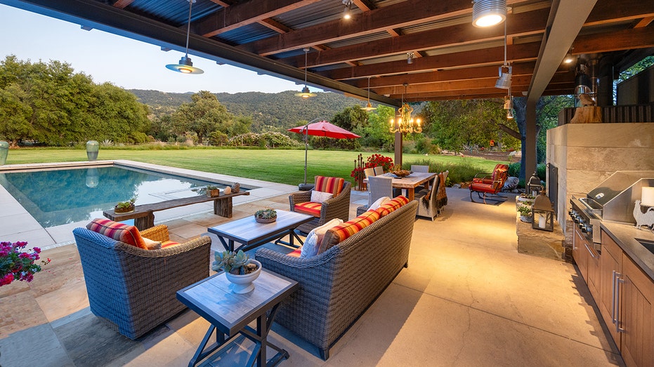 The backyard features a patio with an outdoor kitchen and a pool.