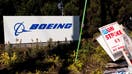 Picket signs near a Boeing sign as workers picket outside the Boeing Co. manufacturing facility during a strike in Renton, Washington, US, on Thursday, Oct. 3, 2024. Boeing Co. factory workers walked off the job for the first time in 16 years, halting manufacturing across the planemakers Seattle hub after members of its largest union voted overwhelmingly to reject a contract offer and go on strike. 