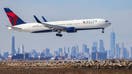 A Boeing 767 passenger aircraft of Delta airlines arrives from Dublin at JFK International Airport in New York as the Manhattan skyline looms in the background on February 7, 2024.