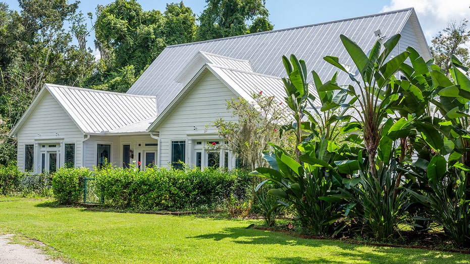 The home's exterior is lined with lush green grass and various plants.