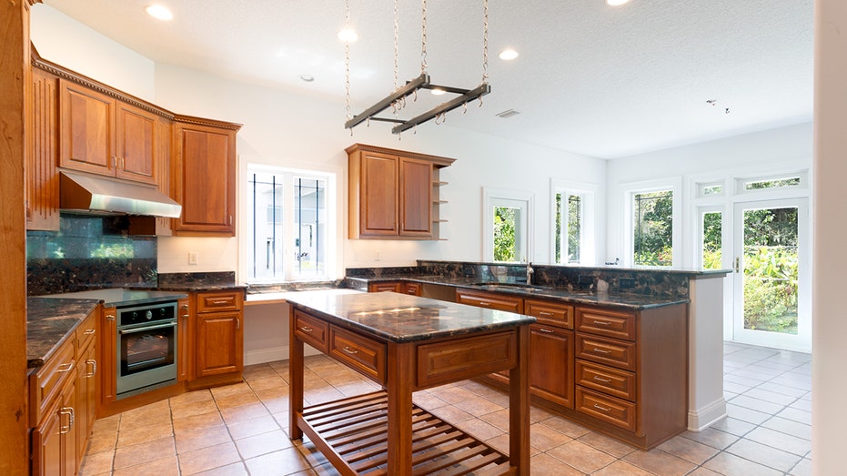 The kitchen features a center island, a unique light fixture and a door leading to the backyard.