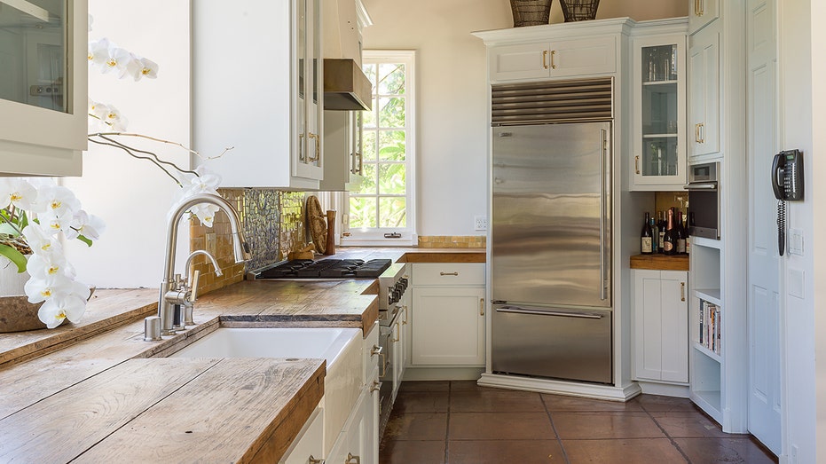 The narrow kitchen features a sink placed underneath a window looking out onto the yard.