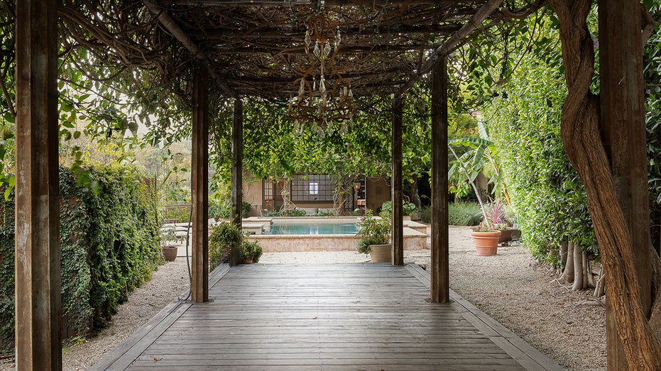 The pool is accessed through a vine-laced trellis.