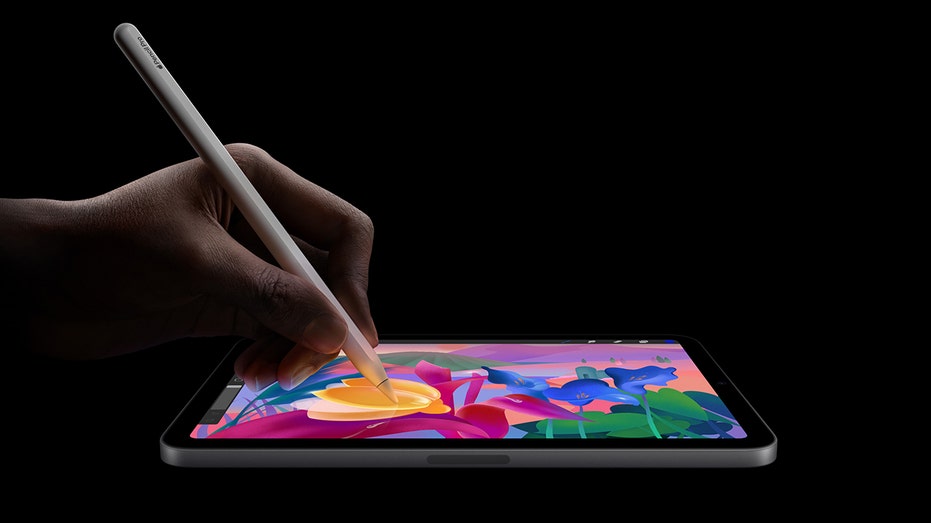 A person using an Apple Pencil Pro with an iPad Mini