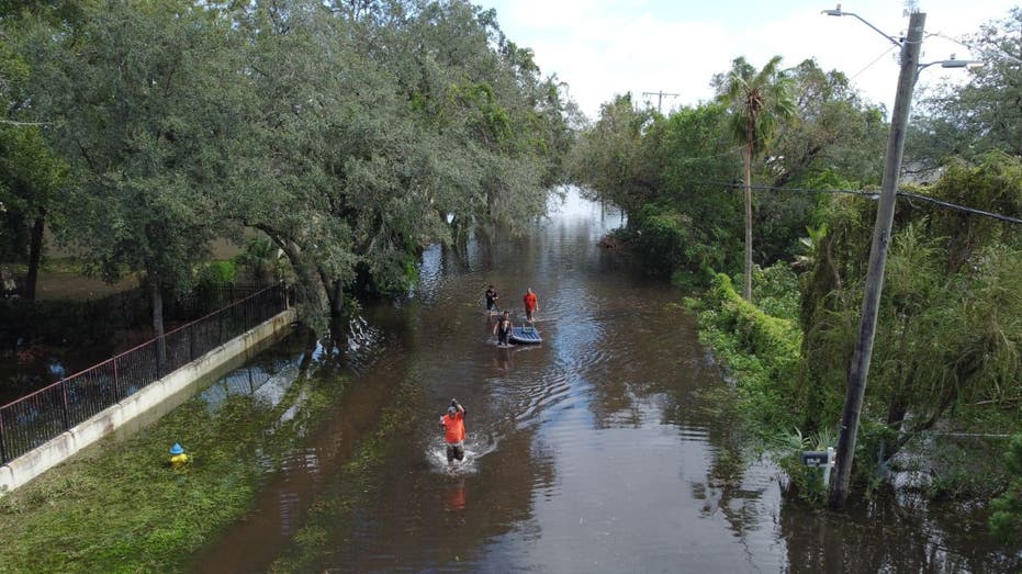 people walking through floodwaters near power lines in Tampa