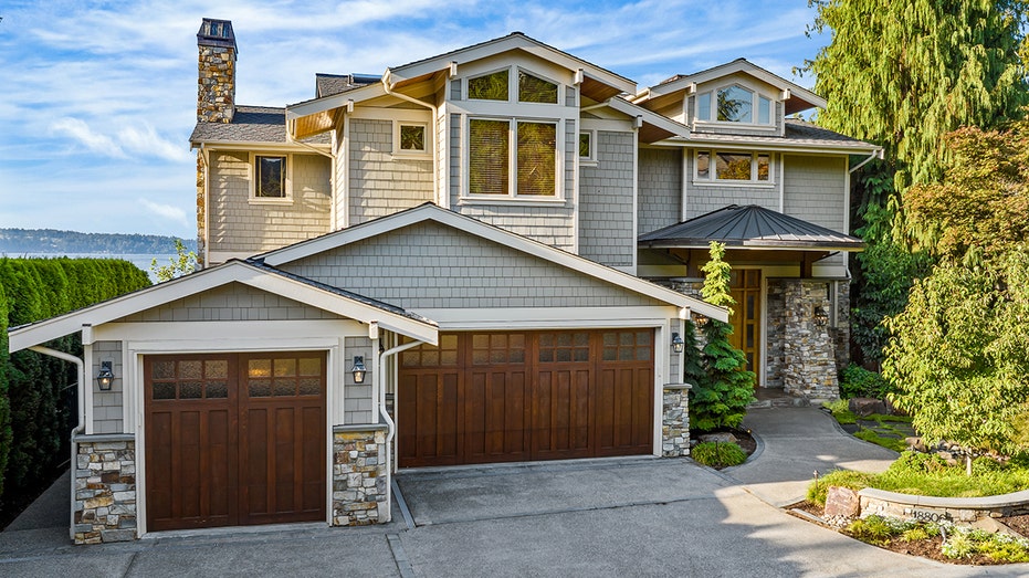 The home is surrounded by tall hedges and trees.