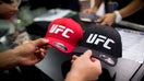 A man browses hats displaying the Ultimate Fighting Championship (UFC) logo at a merchandise kiosk during UFC Fight Night at Cotai Arena, inside the Venetian Macao resort and casino, operated by Sands China Ltd., a unit of Las Vegas Sands Corp., in Macau, China, on Saturday, Aug. 23, 2014. UFC, the largest pay-per-view event provider, broadcasts to more than 800 million homes worldwide.