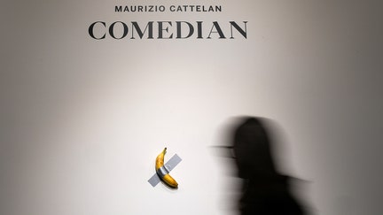 NEW YORK, NEW YORK - OCTOBER 25: People view Maurizio Cattelan's "Comedian" during a press preview for Sotheby's Evening Auction on October 25, 2024 in New York City. The conceptual piece, a banana duct-taped to a wall, went viral in 2019 and one of its three editions is estimated to sell for between $1 million to $1.5 million. (Photo by John Nacion/Getty Images)