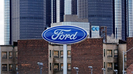 FILE - Ford Motor Co. signage is displayed outside of a dealership as the General Motors Co. (GM) headquarters building stands in the distance in Detroit, Michigan, U.S., on Monday, April 1, 2013.  - Fox Business News