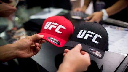 A man browses hats displaying the Ultimate Fighting Championship (UFC) logo at a merchandise kiosk during UFC Fight Night at Cotai Arena, inside the Venetian Macao resort and casino, operated by Sands China Ltd., a unit of Las Vegas Sands Corp., in Macau, China, on Saturday, Aug. 23, 2014. UFC, the largest pay-per-view event provider, broadcasts to more than 800 million homes worldwide.