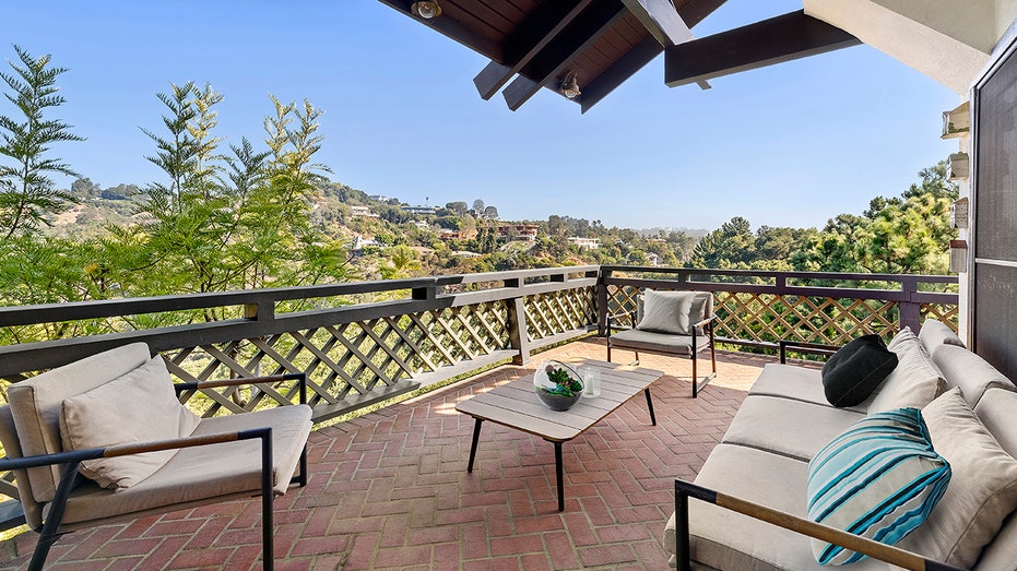 The covered patio features brick flooring and an outdoor seating area.