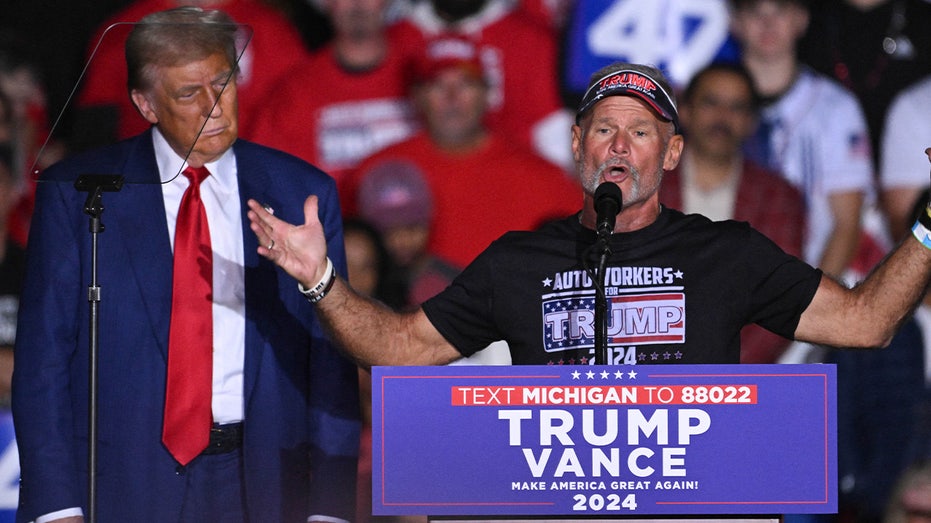 Former US President and Republican presidential candidate Donald Trump listens as autoworker Brian Pannebecker