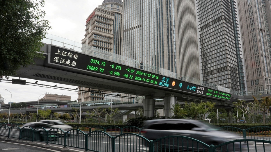 Cars travel past a pedestrian overpass with a display of stock information at the Lujiazui financial district in Shanghai, China, on Nov. 7, 2024.