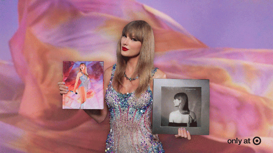 Taylor Swift holding copies of "The Eras Tour Book" and "The Tortured Poets Department: The Anthology"