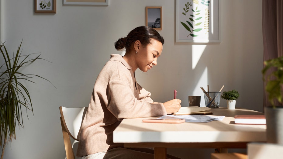 A woman writing in a journal at a desk