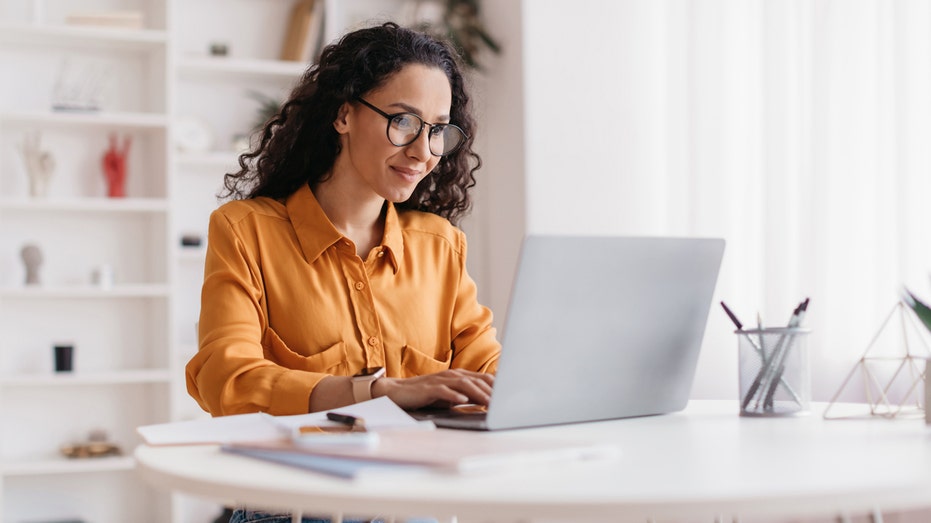 A woman working on her laptop in a home office