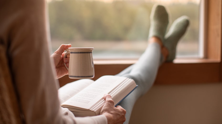 A woman is reading a book by the window