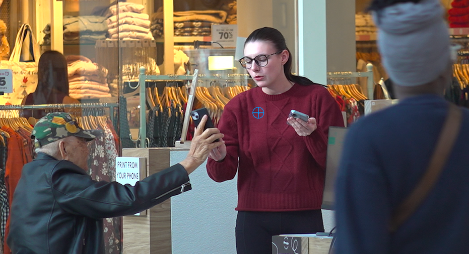 A man in a wheelchair shows something on his phone to a lady.