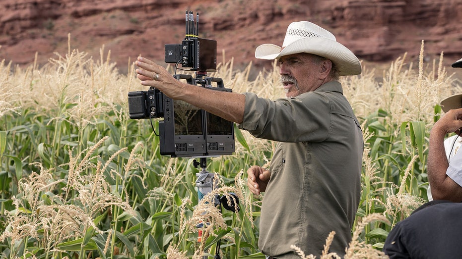 Kevin Costner standing by a camera directing in Utah