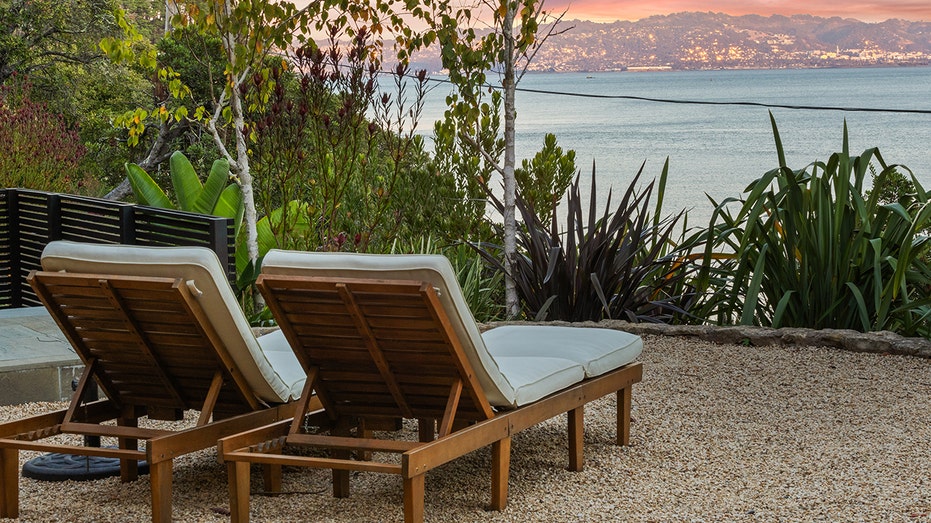 Two chaise lounges look out towards the water with a sunset