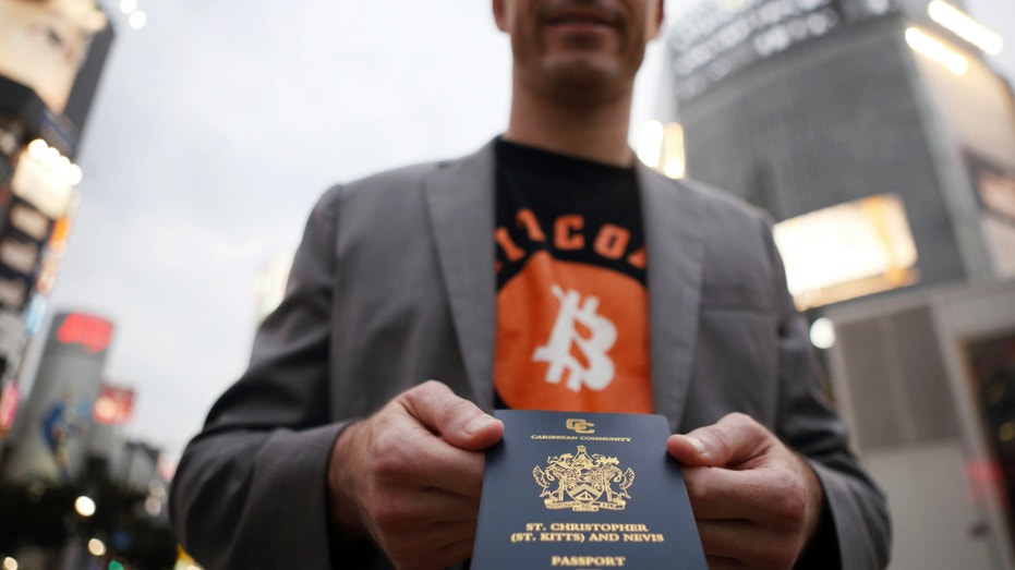 Roger Ver holds his passport as he poses for a photograph in the Shibuya district of Tokyo, Japan, on June 4, 2014.