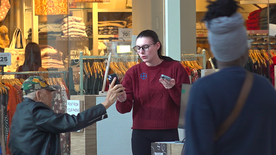 A man in a wheelchair shows a lady on his phone.