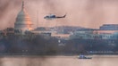 A helicopter flies near the crash site of the American Airlines plane on the Potomac River after the plane crashed on approach to Reagan National Airport.