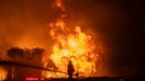 LOS ANGELES, CALIFORNIA - JANUARY 8: A firefighter stands on top of a fire truck to battle the Palisades Fire while it burns homes on the Pacific Coast Highway amid a powerful windstorm on January 8, 2025 in Los Angeles, California. The fast-moving wildfire has grown to more than 2900-acres and is threatening homes in the coastal neighborhood amid intense Santa Ana Winds and dry conditions in Southern California. (Photo by Apu Gomes/Getty Images)
