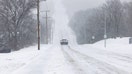 A vehicle cautiously drives down a snowy road on Jan. 5, 2025 in Shawnee, Kansas.