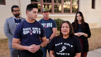 Riverside, CA - December 19: Assemblymembers Bill Essayli, left front, and Leticia Castillo, right front, take turns speaking at a news conference "about the preferential treatment biological boys are receiving" and calling for the resignation of Riverside Unified Superintendent Renee Hill and brought it up during community comments discussing the issue of transgender athletes competing in girls high school sports at the Riverside Unified School District meeting Thursday, Dec. 19, 2024. (Allen J. Schaben / Los Angeles Times via Getty Images)