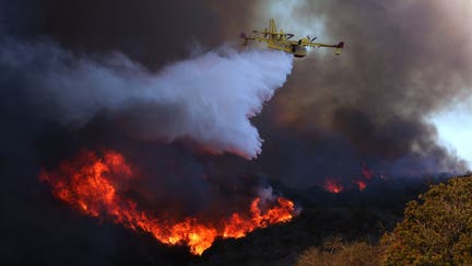 A firefighting plane makes a drop on the Palisades Fire in Pacific Palisades on Jan. 7. The Palisades fire is being pushed by gusting Santa Ana winds that were expected to continue for two more days.