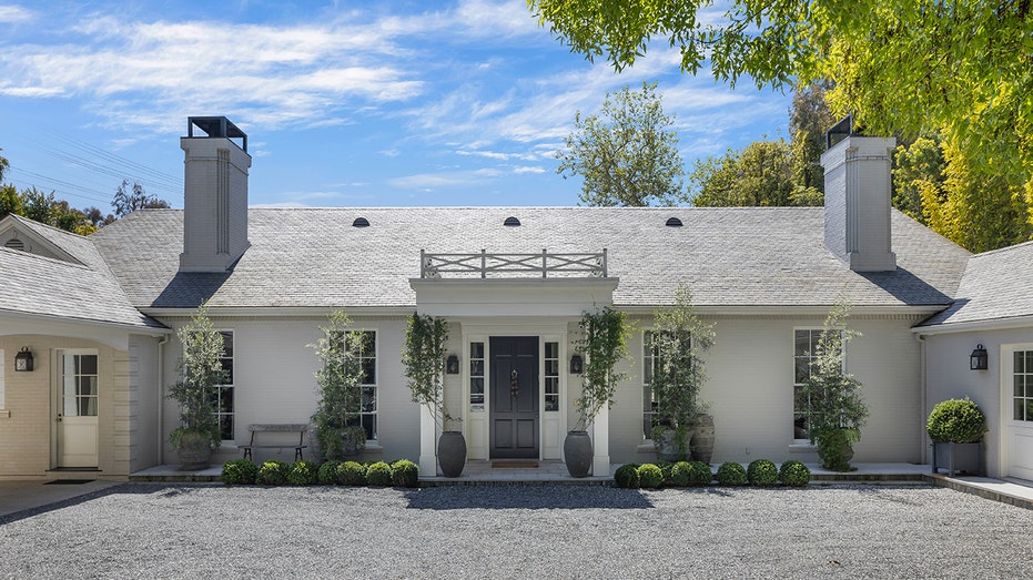 The outside of the house is lined with small circular hedges.