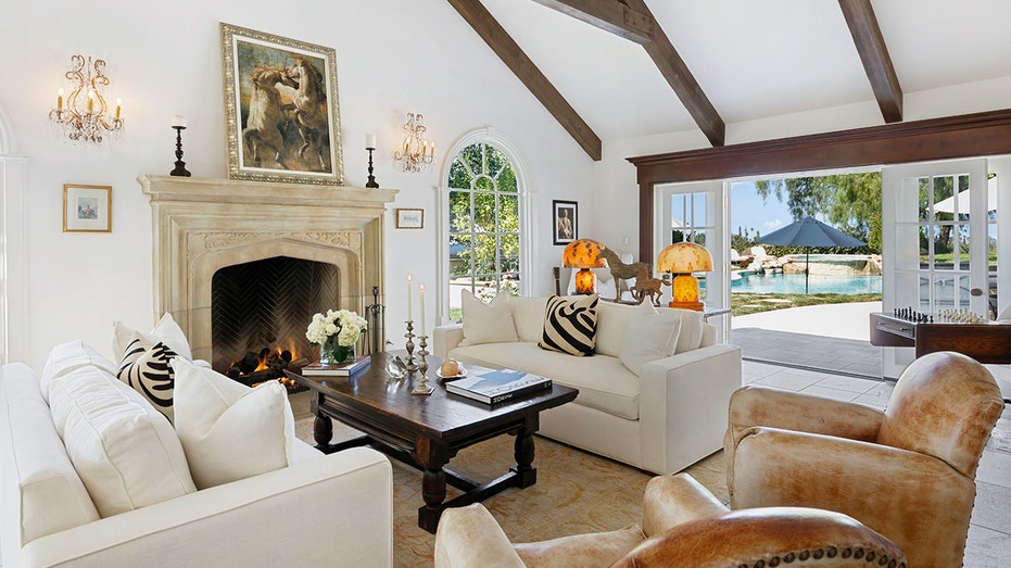 The living room features exposed wooden beams, a wood-burning fireplace and access to the yard.