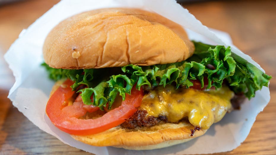 Close up of a cheeseburger with tomato and lettuce in a paper wrapper at Shake Shack, Walnut Creek, California, August 25, 2024. (Photo by Smith Collection/Gado/Getty Images)