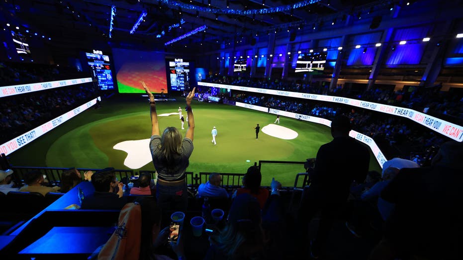 PALM BEACH GARDENS, FLORIDA - JANUARY 07: A fan cheers in the stands during play on the the ninth hole during the TGL presented by SoFi match between the New York Golf Club and The Bay Golf Club at SoFi Center on January 07, 2025 in Palm Beach Gardens, Florida. (Photo by Mike Ehrmann/TGL/TGL Golf via Getty Images)