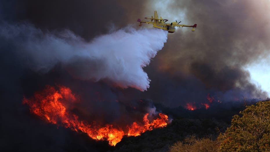 PACIFIC PALISADES, CALIF January 7, 2024 A fire plane makes a drop on the Palisades Fire in Pacific Palisades on Tuesday, January 7. The Palisades fire is being pushed by Santa Ana winds that are expected to continue for two more days. (Brian van der Brug/Los Angeles Times via Getty Images)