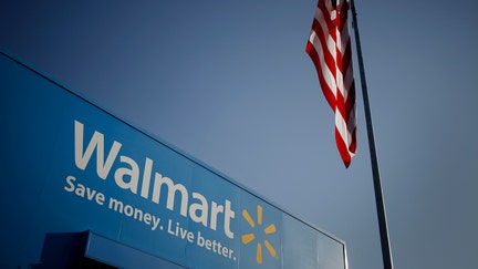 An American flag flies near signage displayed outside of the Walmart Stores Inc. headquarters building in Bentonville, Arkansas, U.S., on Wednesday, July 29, 2015.