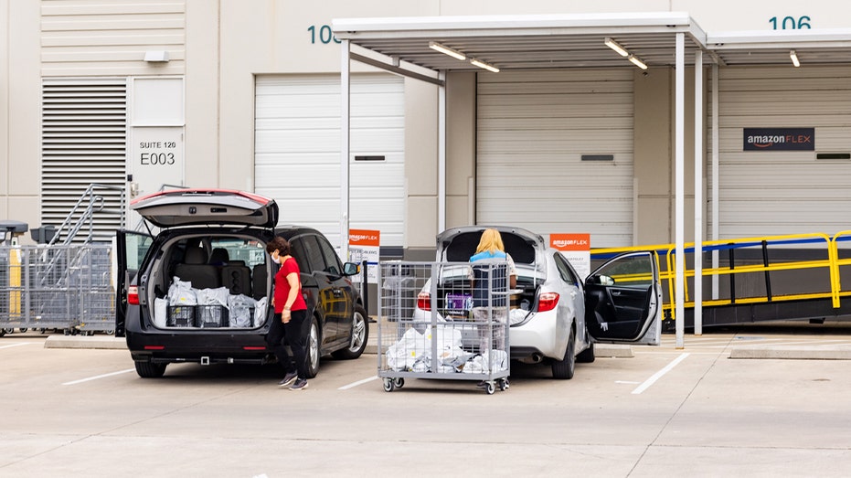 Various workers are loading cars with orders at Amazon delivery channel