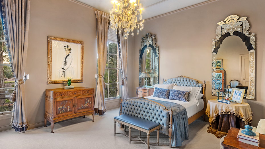 One of the bedrooms featured many windows, beige walls and a chandelier hanging from the ceiling.