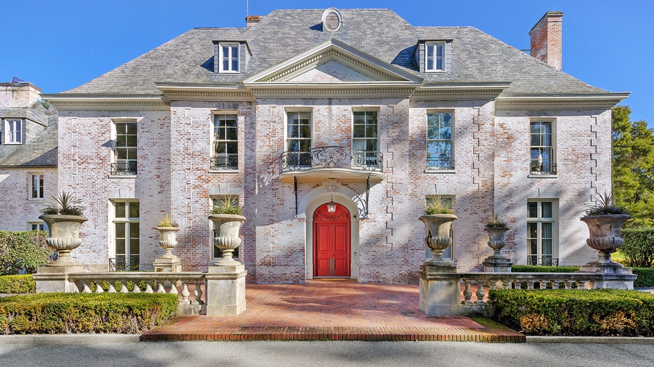 A brick courtyard leads to the red front door.