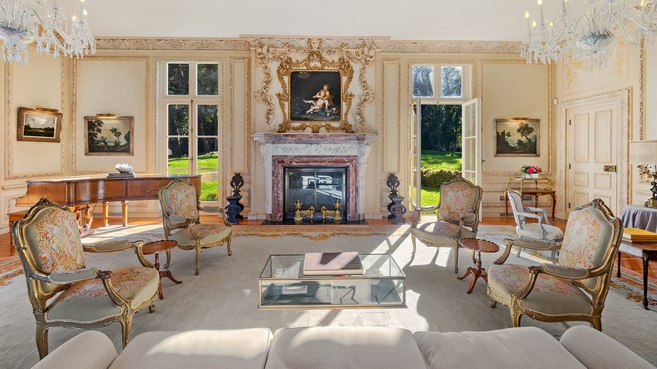 The living room includes a decorated fireplace, from floor to ceiling and a tail piano.