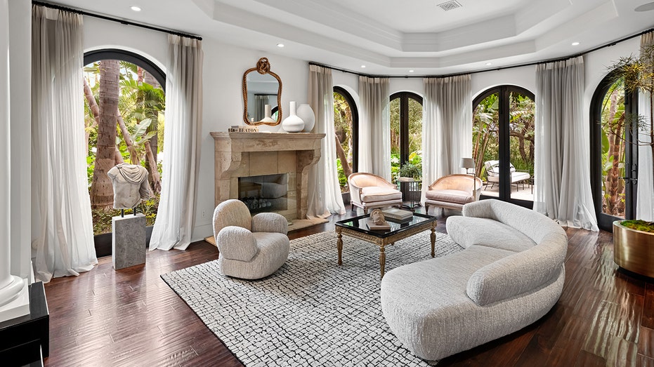 The living room includes a stone marble fireplace and arched windows.