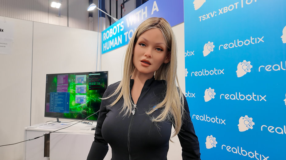 A robot that looks like a woman stares at the camera